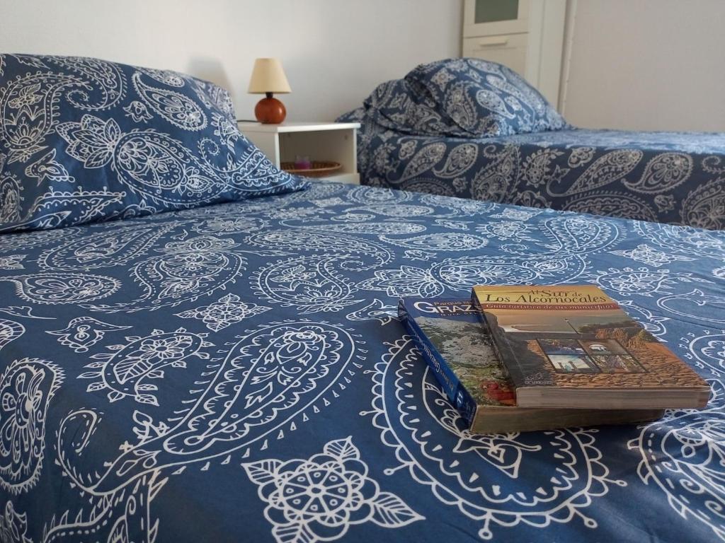 un libro sentado en la parte superior de una cama en Habitación privada económica y acogedora cerca de Cádiz, en Puerto Real