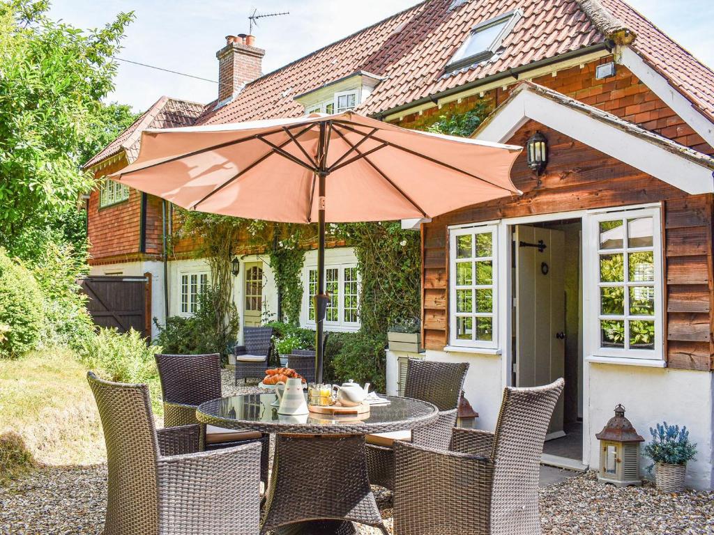 une terrasse avec une table, des chaises et un parasol dans l'établissement Greenbank Cottage, à Burley