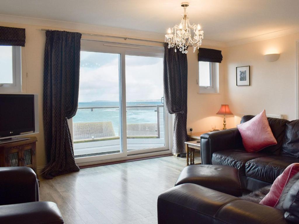 a living room with a couch and a large window at Seaview Apartment - 21 Spinnakers in Newquay