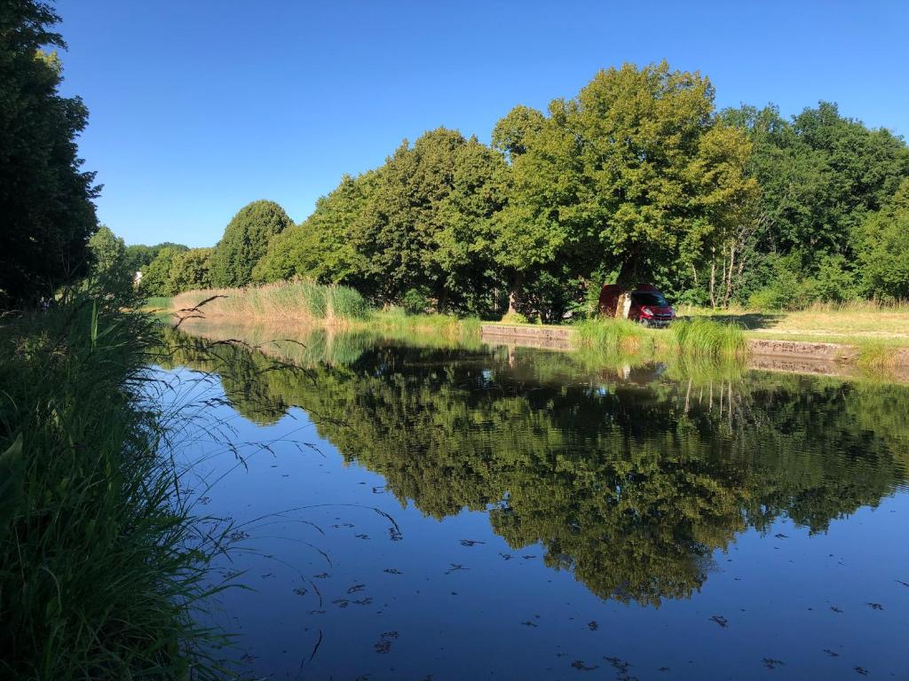 een uitzicht op een rivier met een weerspiegeling van bomen bij Au petit canal de Bavilliers in Bavilliers