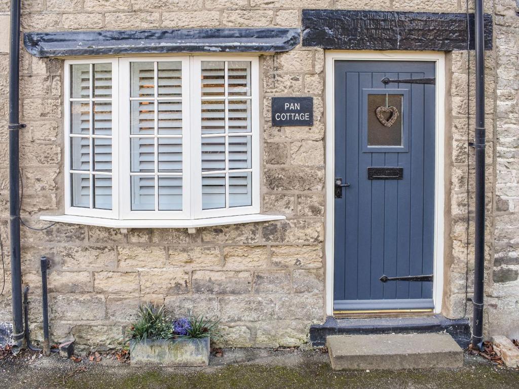 a blue door and window on a stone building at Pan Cottage in Middleton