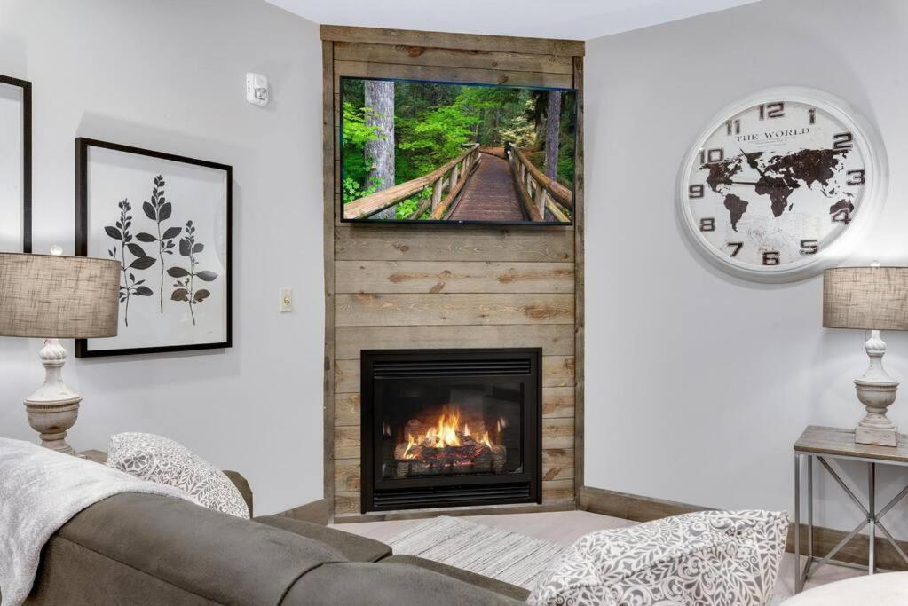 a living room with a fireplace and a clock at Barnwood Suite - Main Street Lodge in Berlin in Berlin