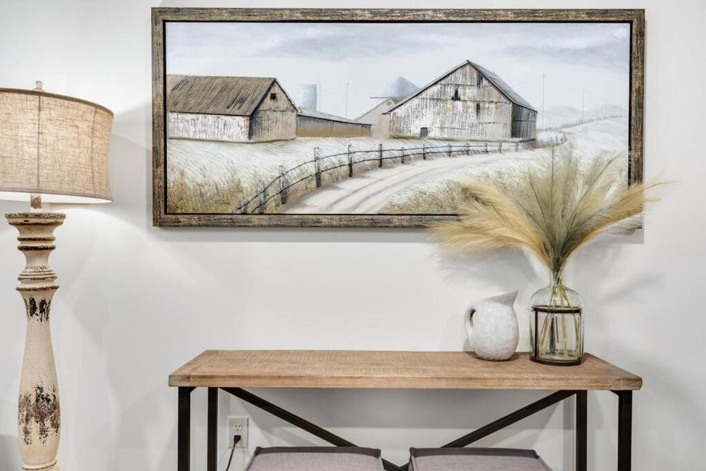 a painting of barns and a table with a lamp at Maple Suite - Main Street Lodge in Berlin in Berlin