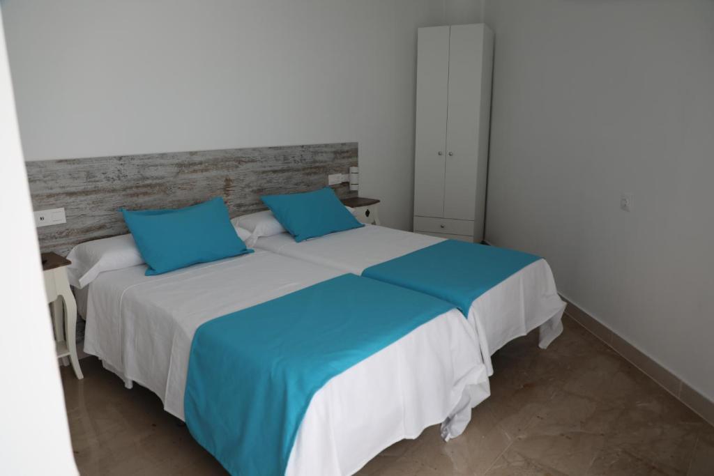 a bedroom with a large bed with blue pillows at Pension Campello The Blue Med in Alicante