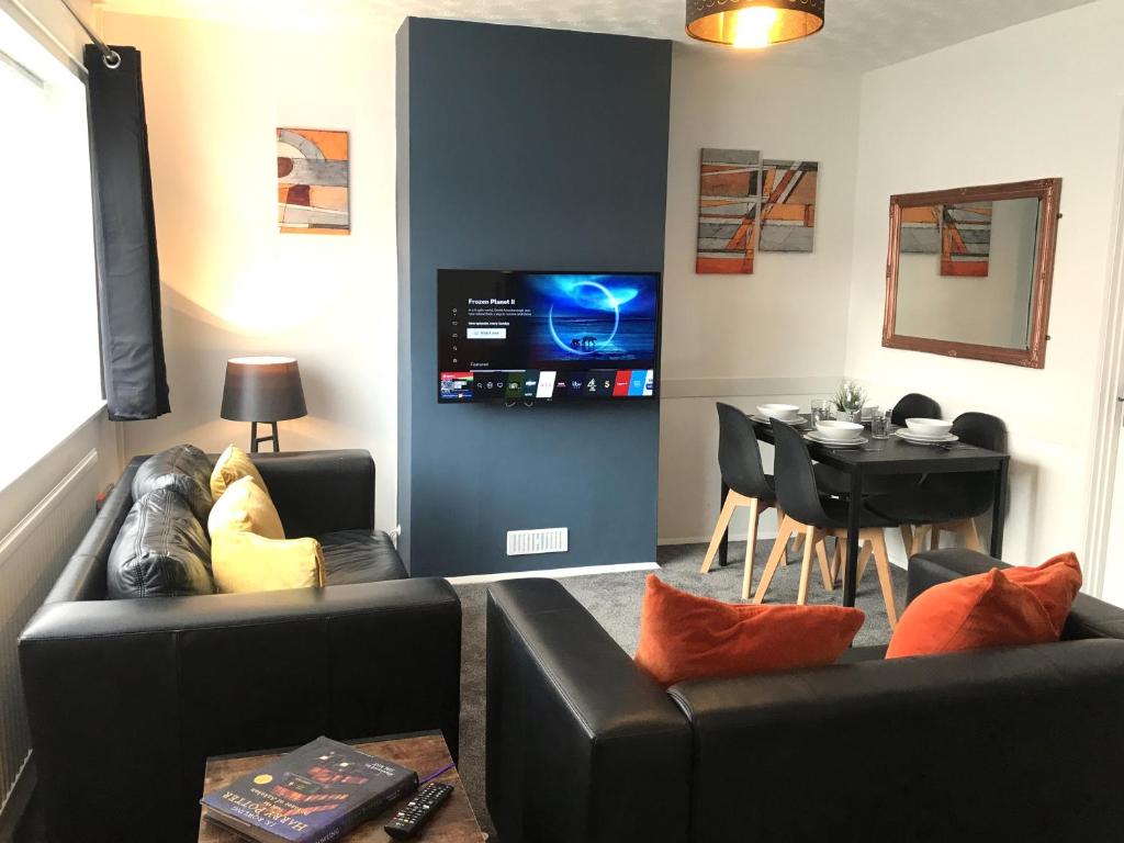 uma sala de estar com dois sofás pretos e uma mesa em Modern 3-bed house with parking Bamber Bridge, Preston em Bamber Bridge