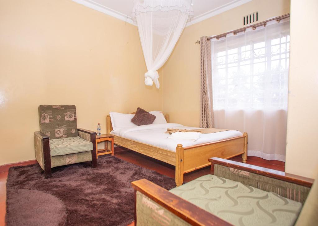 a bedroom with two beds and a chair and a window at The Nest Guest House in Kericho