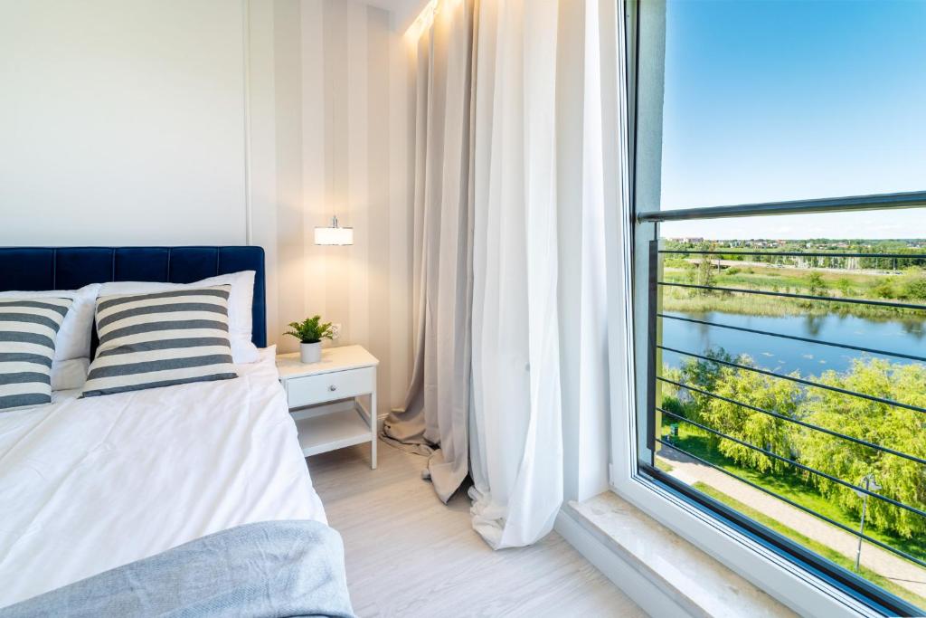ein Schlafzimmer mit einem Bett und einem großen Fenster in der Unterkunft Belle View Apartment in Iława