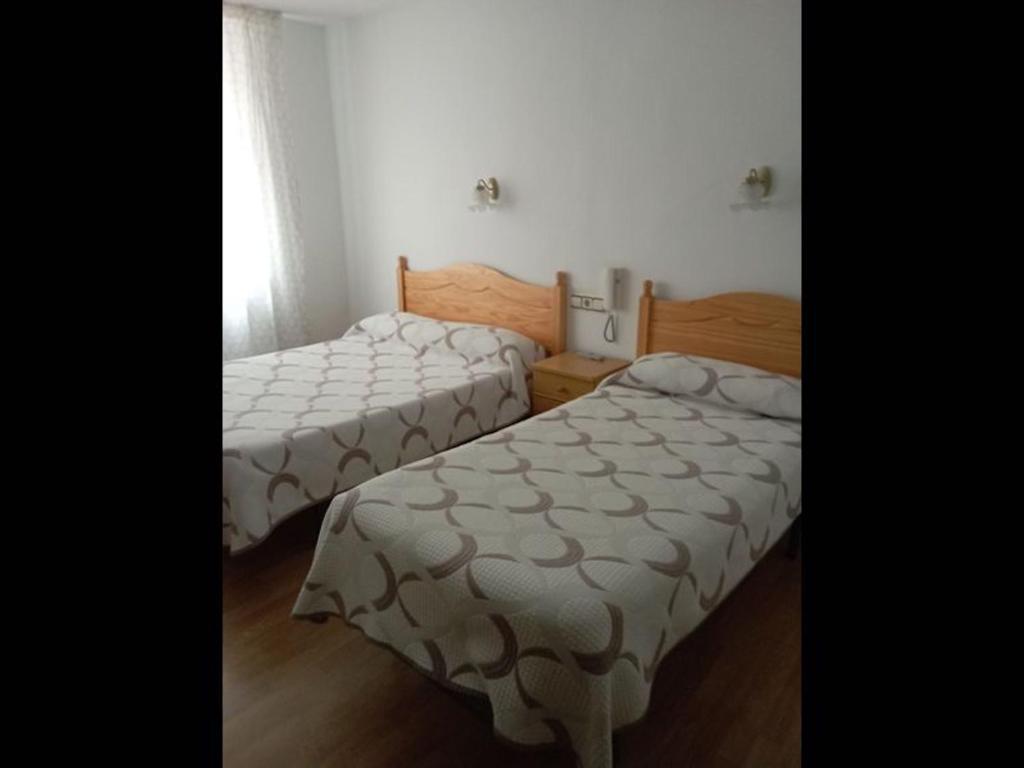 2 camas en una habitación pequeña con mantas blancas en Room in Lodge - Double and single room - Pension Oria 4, en Luarca