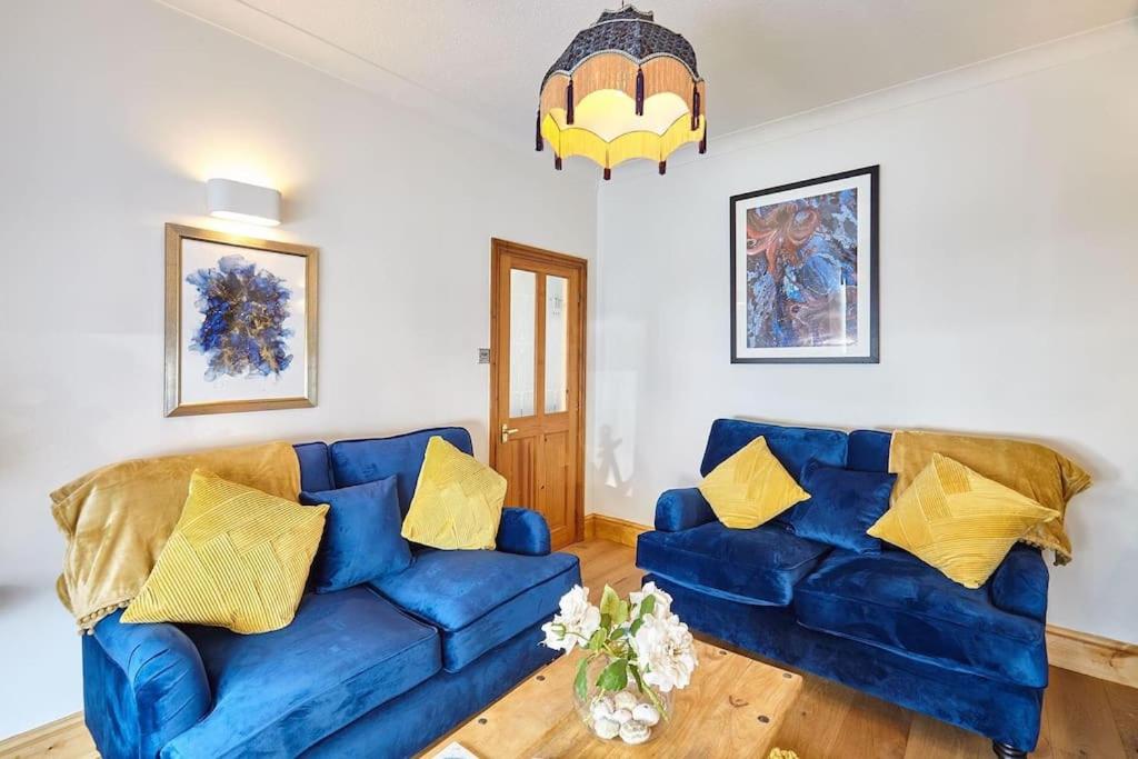 sala de estar con sofá azul y almohadas amarillas en Sea Urchin, en Whitby