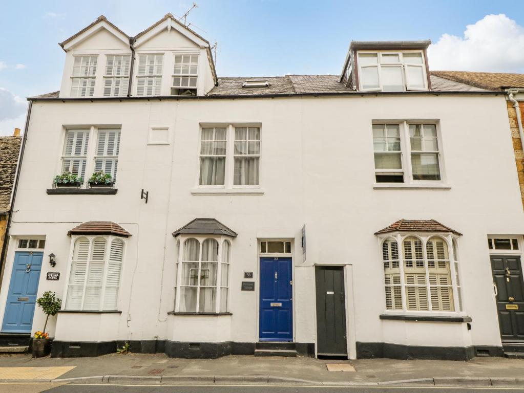 een wit huis met blauwe deuren en ramen bij Primrose Cottage in Cheltenham