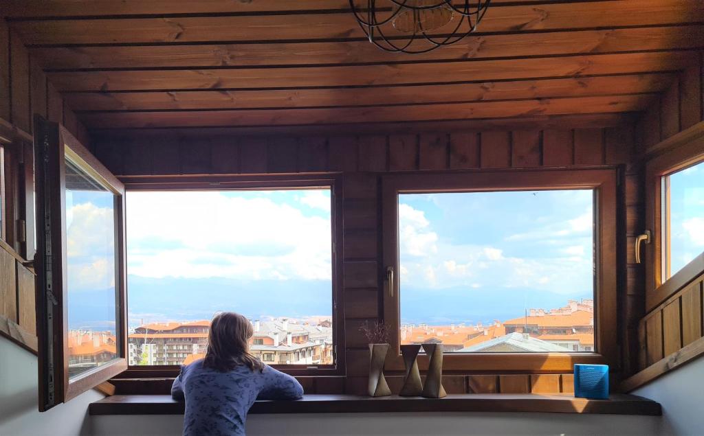 a woman sitting on a bench looking out of a window at Mountain View Resort - Apartment B45 in Bansko