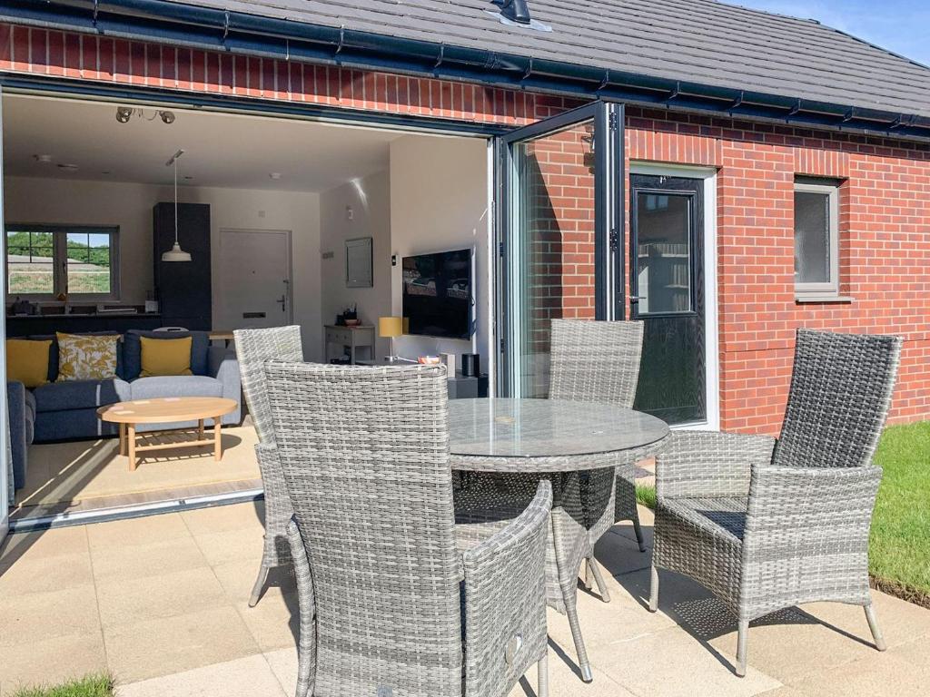 a glass table and chairs on a patio at Hawthorn Cottage in Shirley