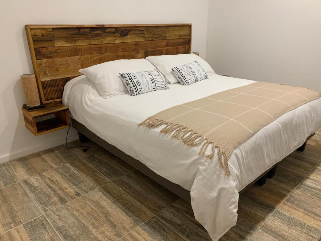 uma cama com lençóis brancos e almofadas num quarto em Cabañas El jardín de Jacinta em Coihaique