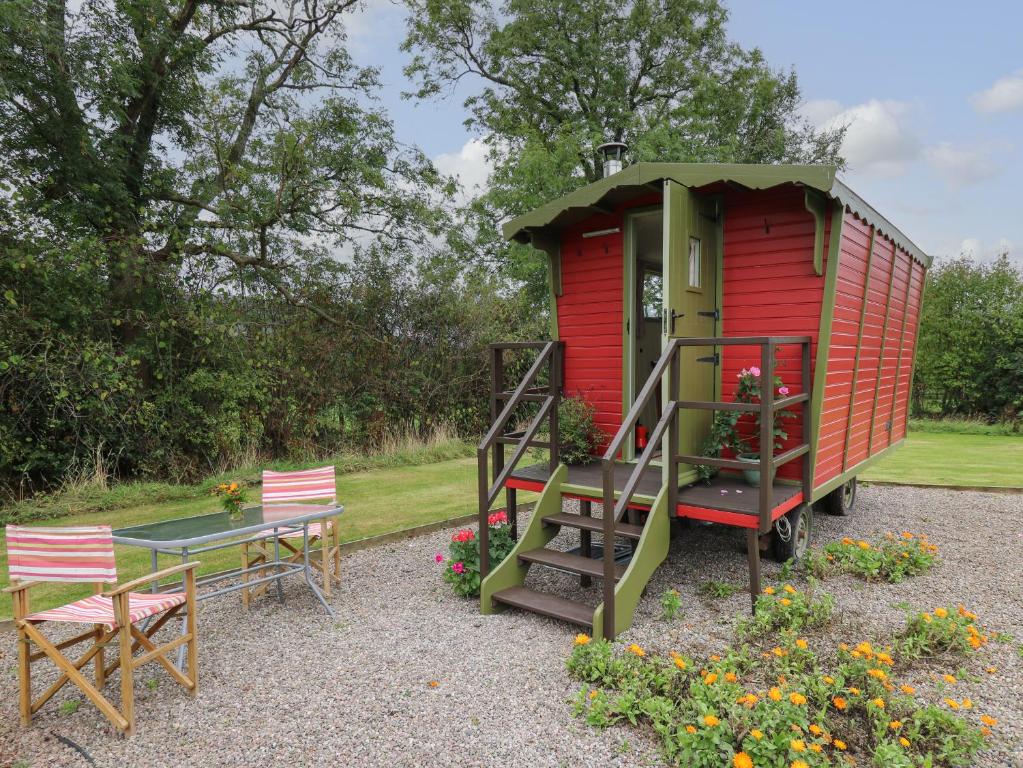 een rood tiny house met een tafel en stoelen bij Tilly Gypsy-style Caravan Hut in Brecon