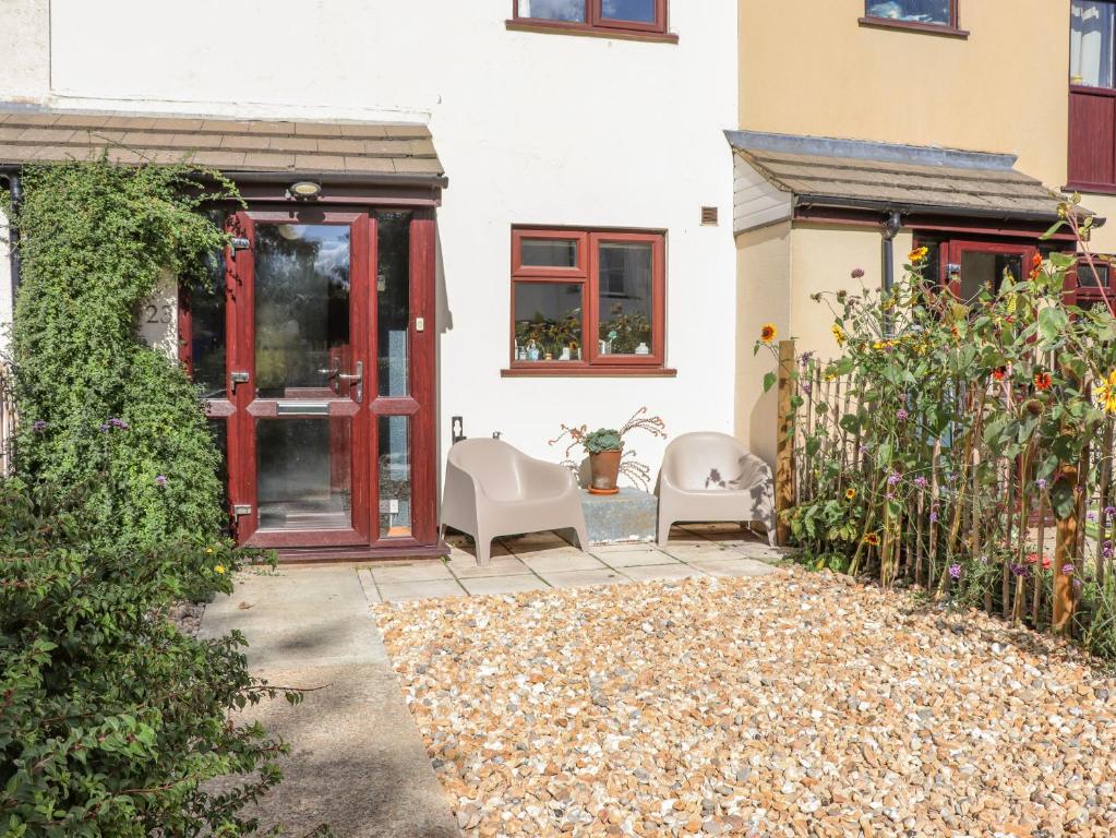 einen Garten mit zwei Stühlen und einer roten Tür in der Unterkunft Coastguard Cottage in Rye