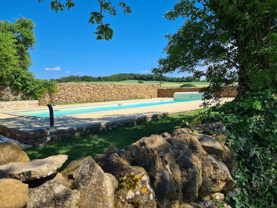 a swimming pool in a yard with rocks at Maison chaleureuse près de Rocamadour in Alvignac