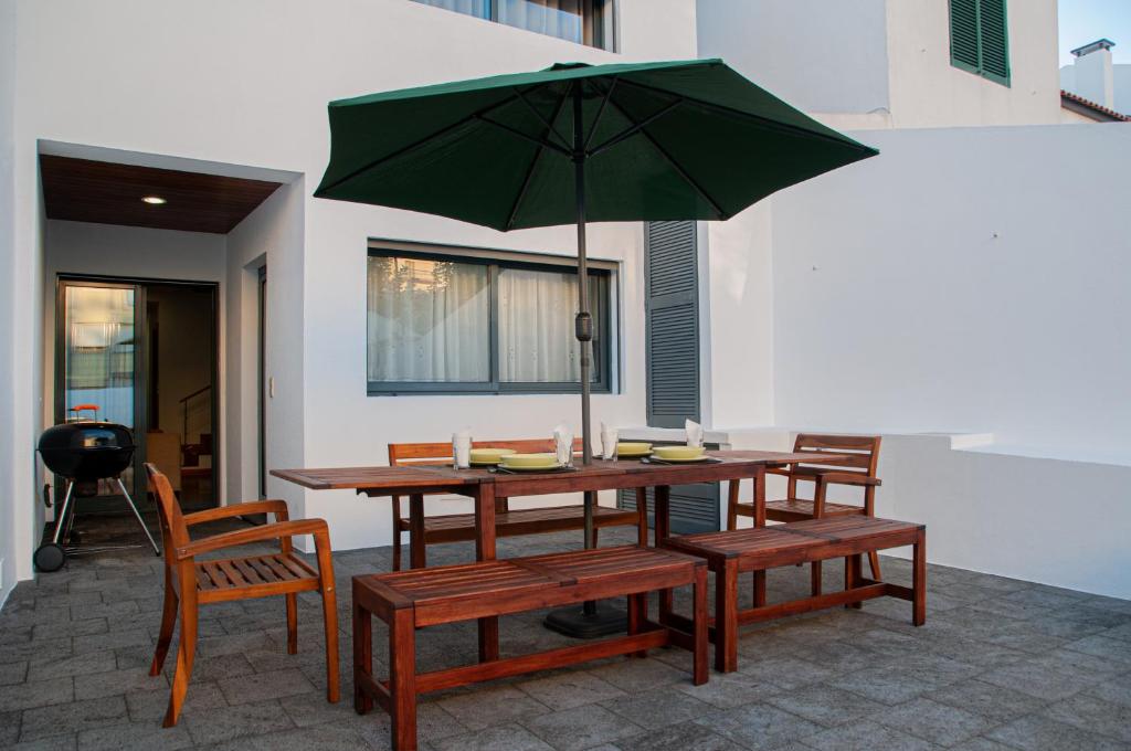 a table and benches with an umbrella on a patio at Sailorman and Friends in Ponta Delgada