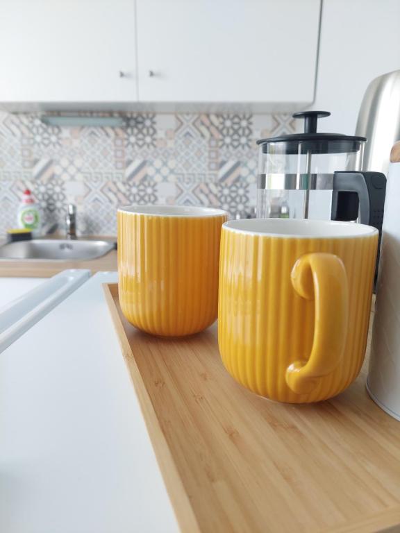 two yellow cups sitting on a cutting board in a kitchen at Pigeon apartment in Kuldīga