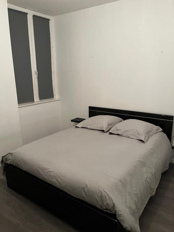 a bedroom with a large bed with white sheets and a window at Le parapluie rouge in Chalons en Champagne