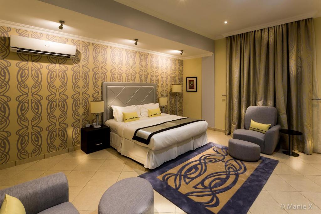 une chambre d'hôtel avec un lit et deux chaises dans l'établissement Morning Side Suites & Spa, à Lagos