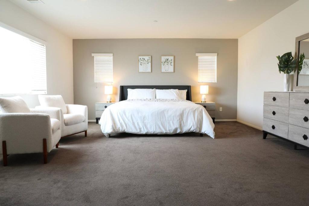 a bedroom with a white bed and a white chair at Cheerful 4 Bedroom Entire House Lots Of Open Space 