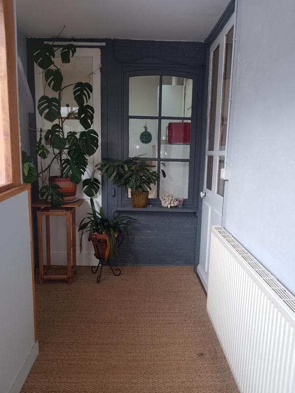 a hallway with potted plants and a door with a window at Le garage in Étretat