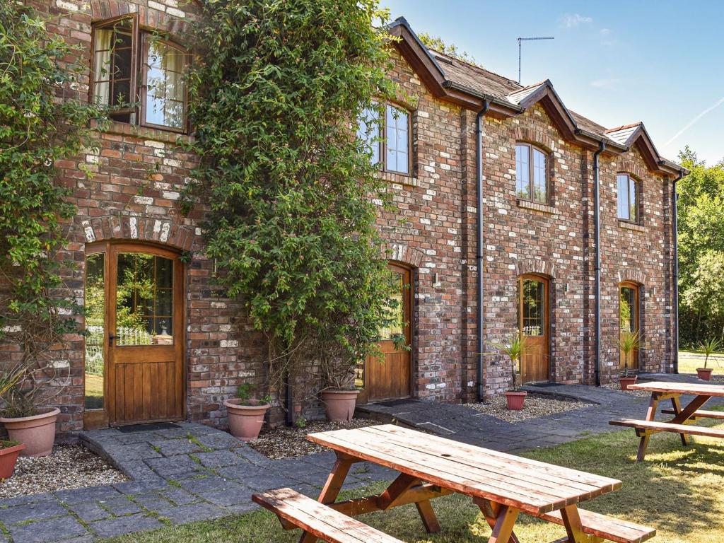 a brick building with two picnic tables in front of it at Poppy Cottage - Uk40102 in Dunvant