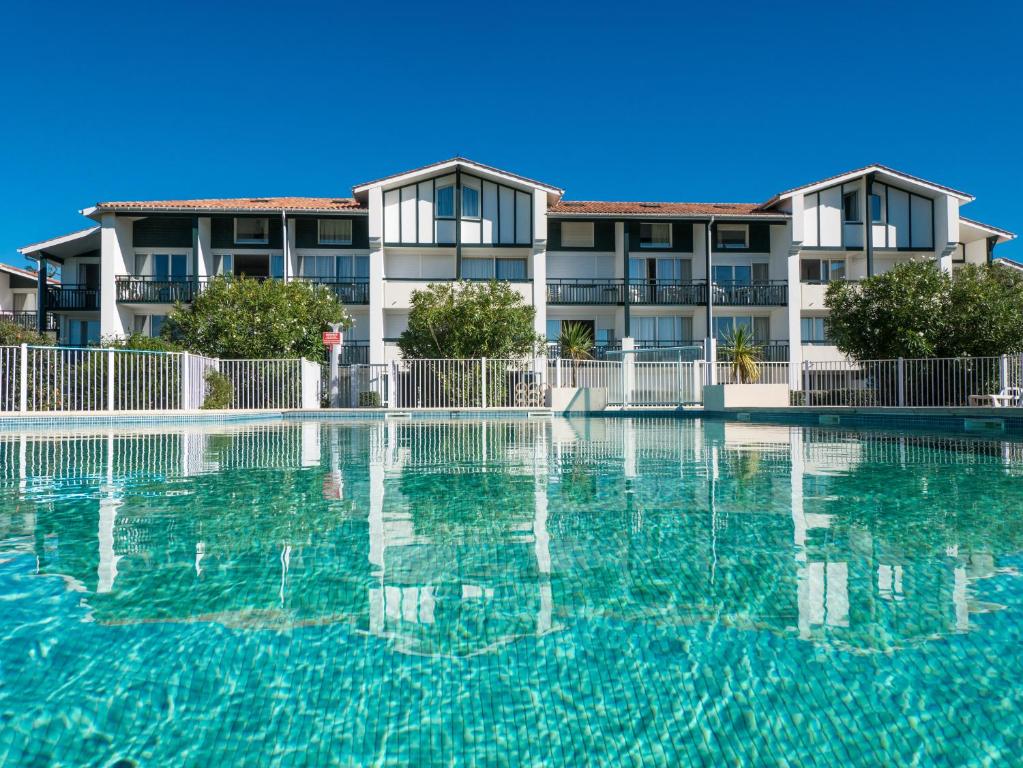 un hôtel avec une piscine en face d'un bâtiment dans l'établissement Résidence Mer & Golf Ilbarritz, à Bidart