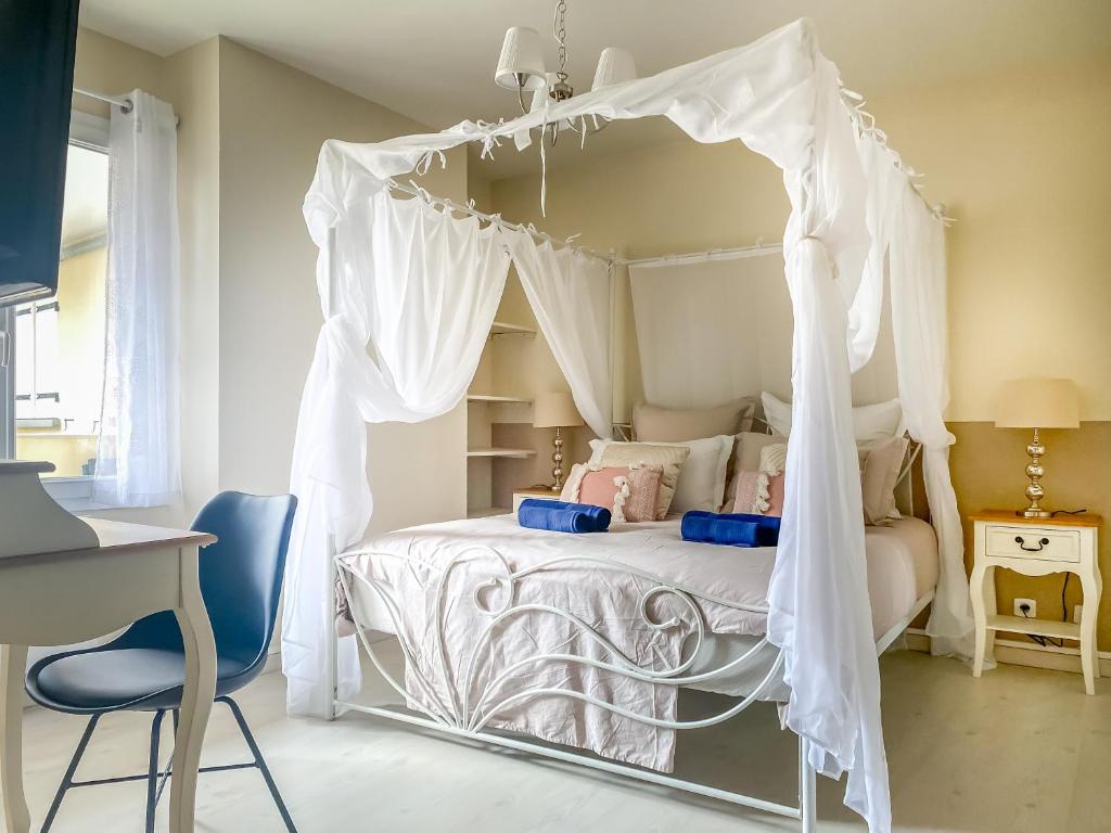 a white canopy bed in a bedroom with a desk and a chair at Fééria - Appartement au calme proche de Disneyland Paris in Chessy