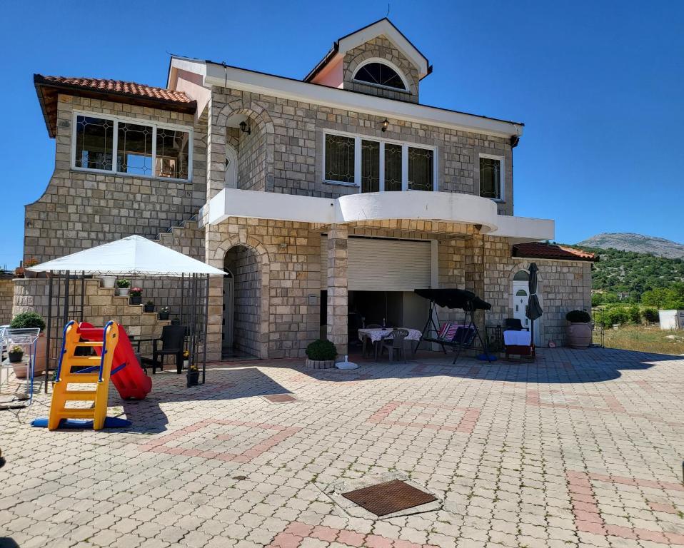 a large brick house with a patio in front of it at Apartmani Lux in Trebinje