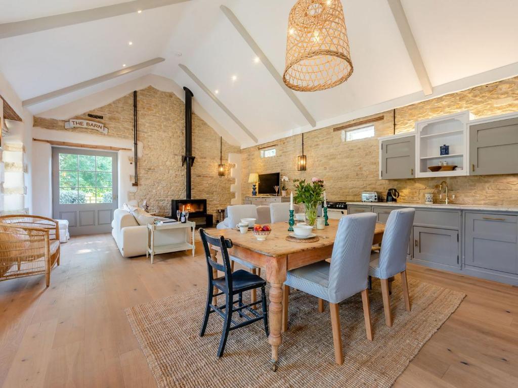 a kitchen and living room with a wooden table and chairs at The Barn in Shipton under Wychwood