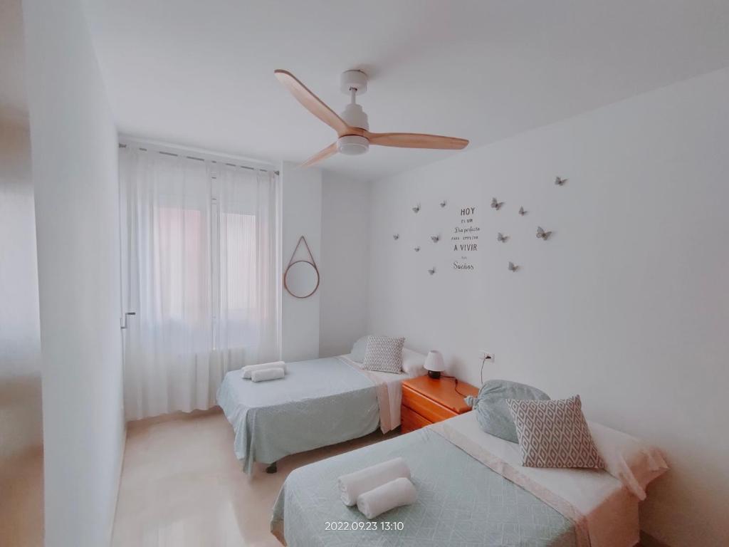um quarto branco com 2 camas e uma ventoinha de tecto em Tirwal Suite Judería em Teruel