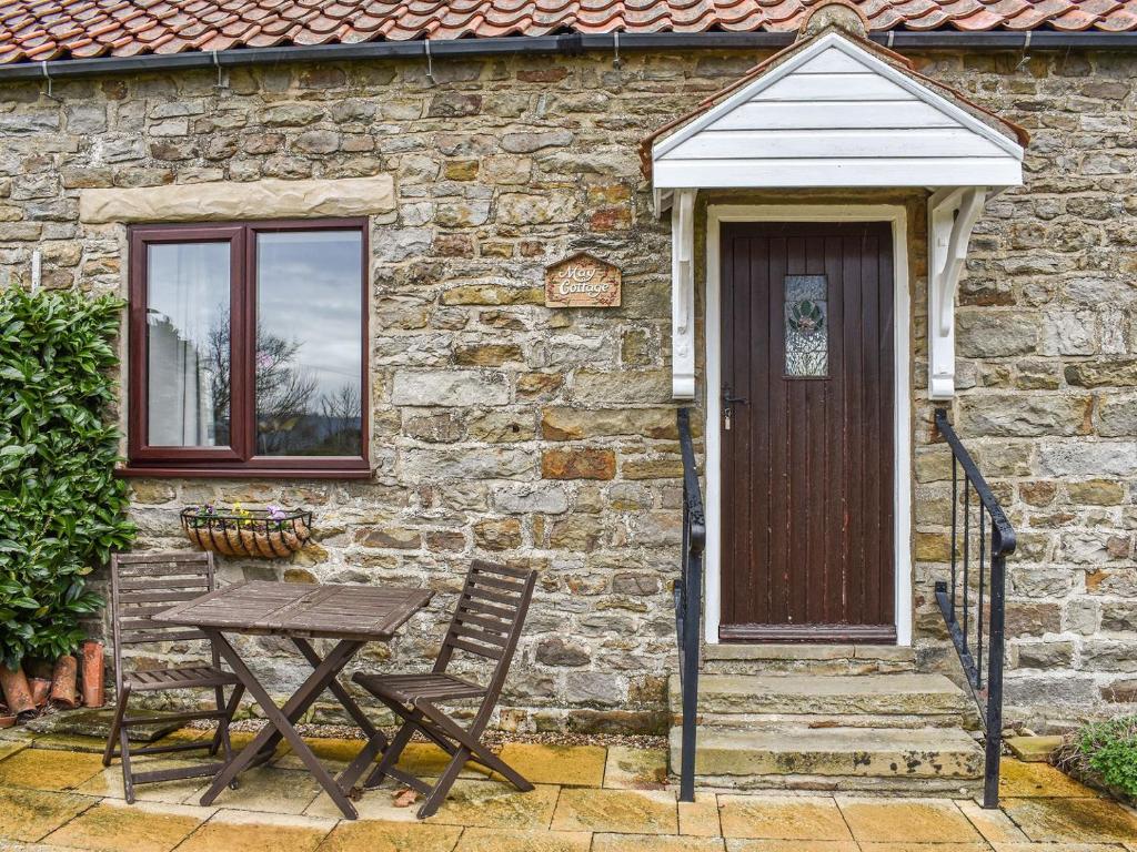 a stone house with a table and a wooden door at May Cottage-uk38279 in Cloughton