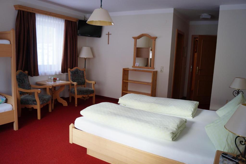 Cette chambre comprend 2 lits et une table. dans l'établissement Landhaus St. Georg, à Saalbach-Hinterglemm