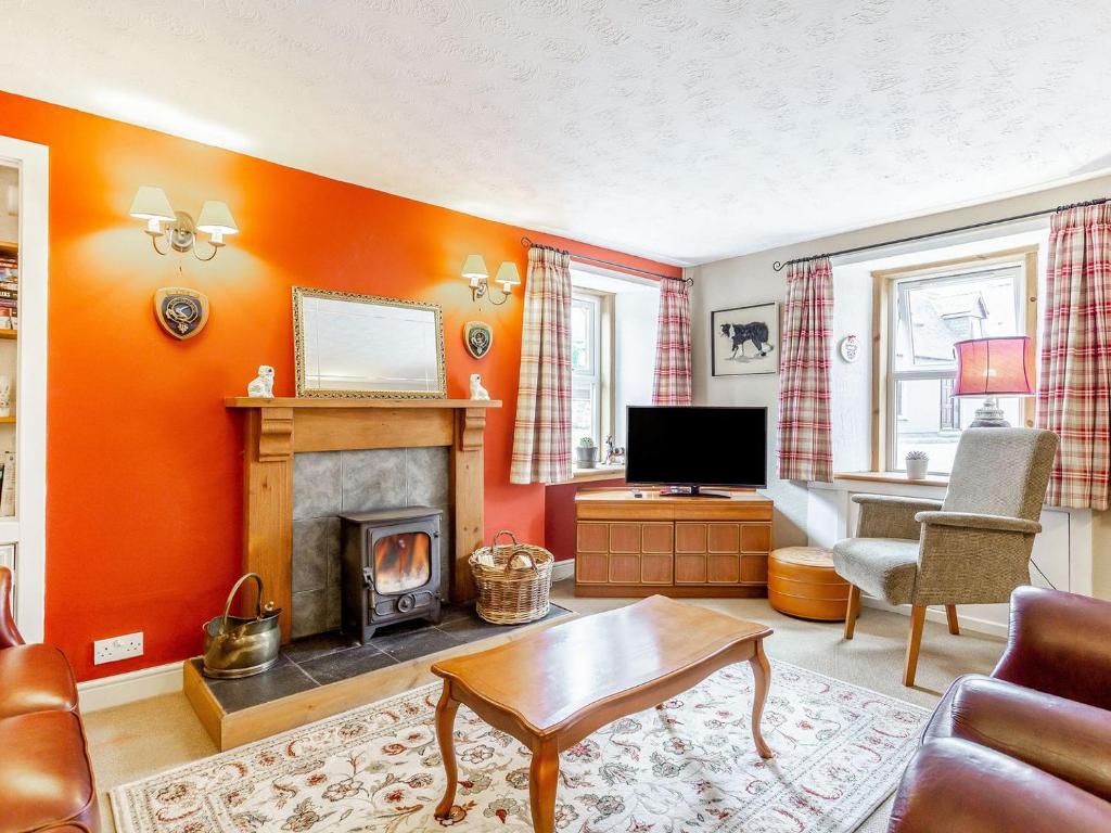 sala de estar con paredes de color naranja y chimenea en Holly Tree Cottage, en Tain