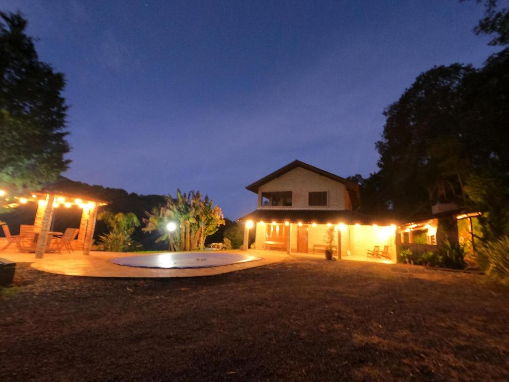 una casa di notte con un cerchio nel cortile di Sítio dos Coqueiros, em meio a natureza com piscina a Carlos Barbosa