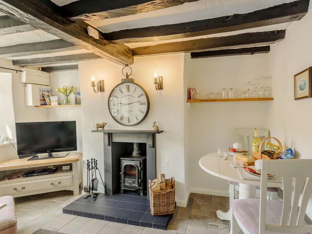 a living room with a fireplace and a clock on the wall at Bimble Cottage in Ingham