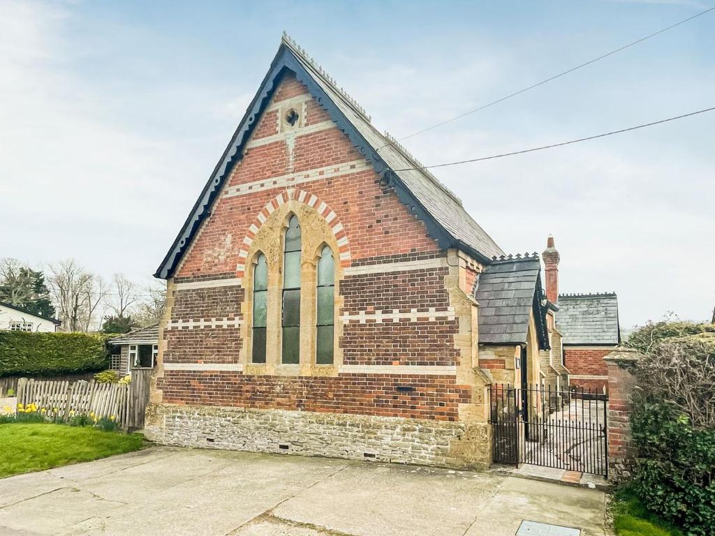 una iglesia de ladrillo rojo con techo negro en The Sunday Schoolroom en Wootton Glanville