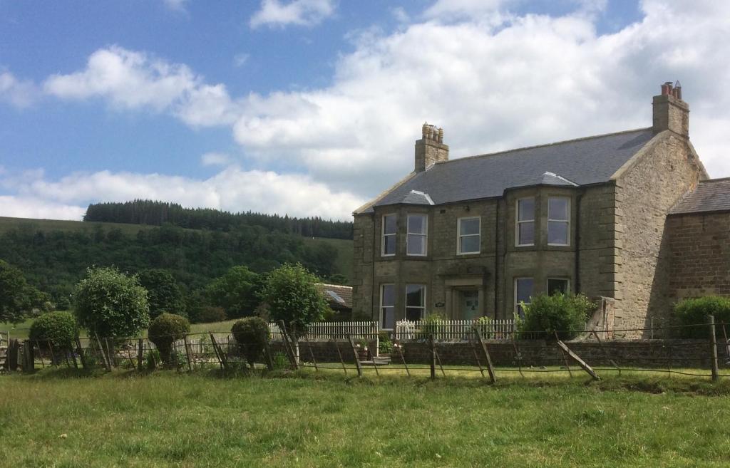 a large brick house with a fence in a field at Ellerton Lodge Bed and Breakfast Swaledale in Richmond