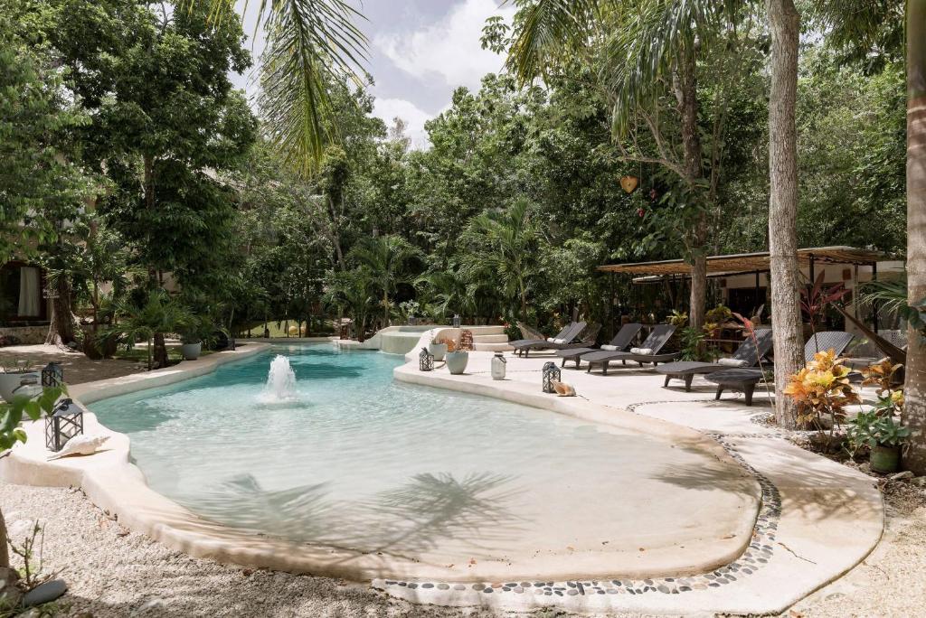 a swimming pool with a fountain in a yard at Cachito de Cielo Luxury Jungle Lodge in Tulum