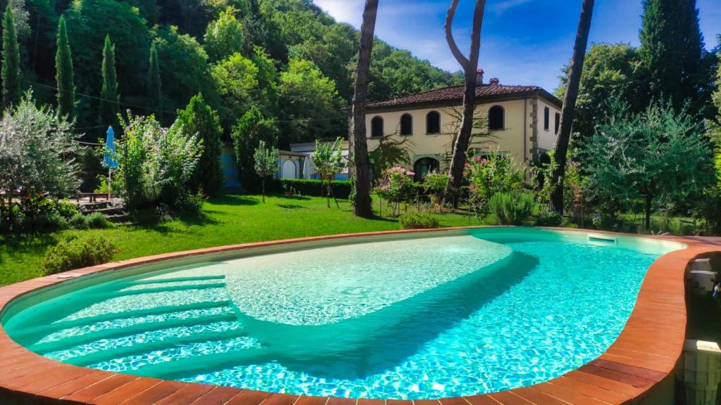 una piscina in un cortile con una casa sullo sfondo di Villa La Ginestra - Charming Country Home a Capolona