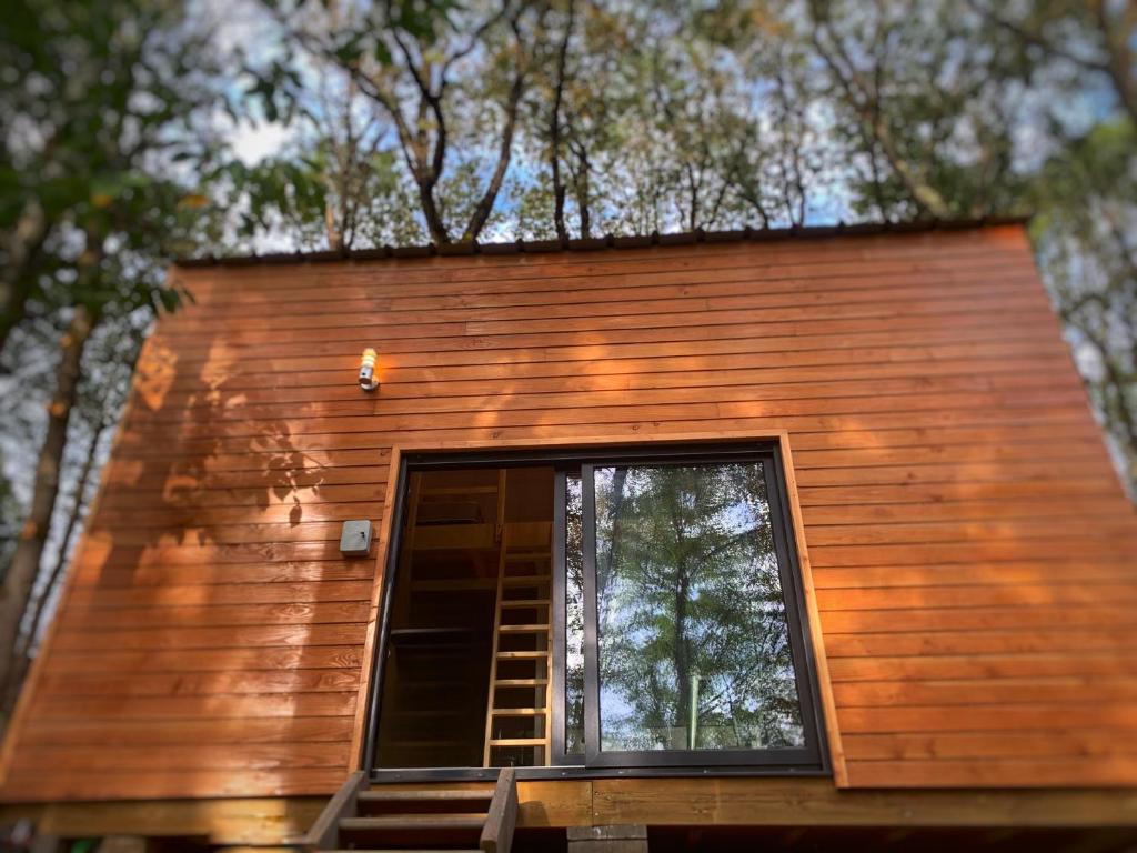 una casa pequeña con una ventana en el bosque en La Cabane de Piquet, en Le Tablier