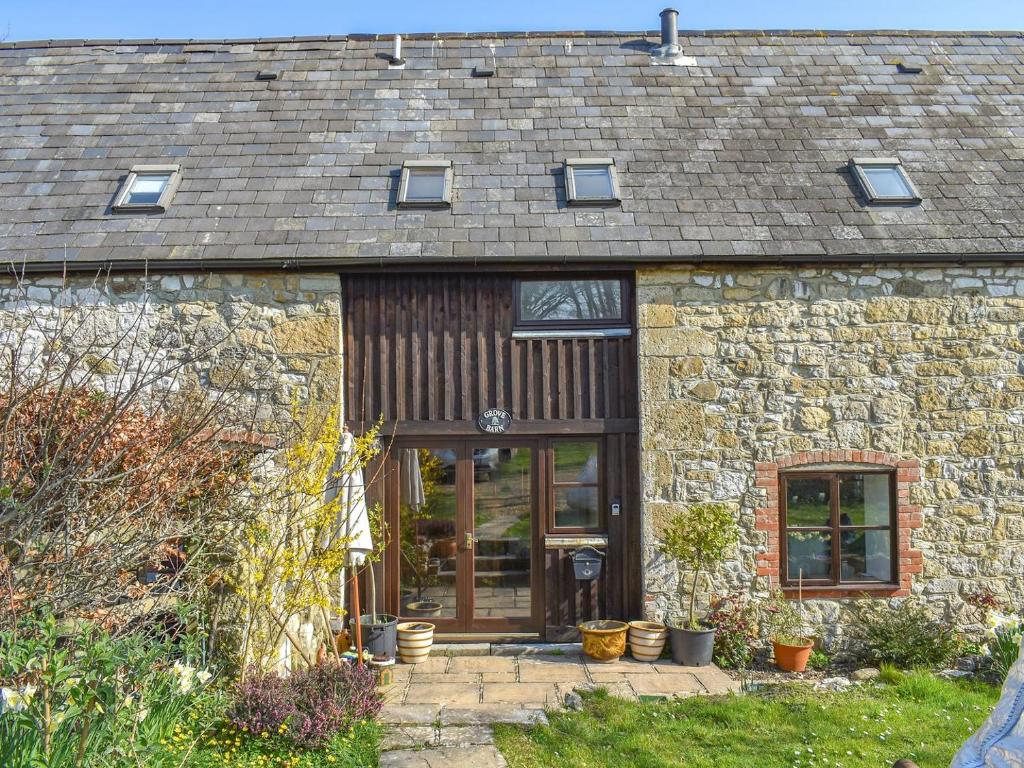 a stone cottage with a wooden door and windows at Grove Barn in Carisbrooke