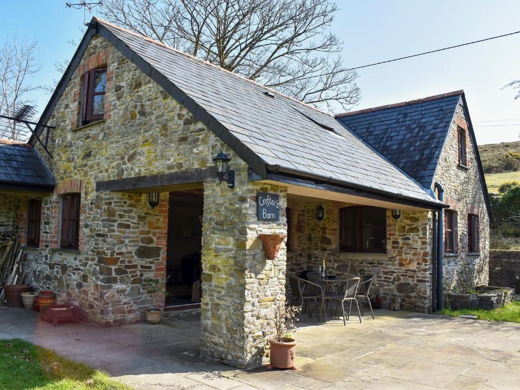 an old stone house with a patio in front of it at Crofters Barn in Brentor