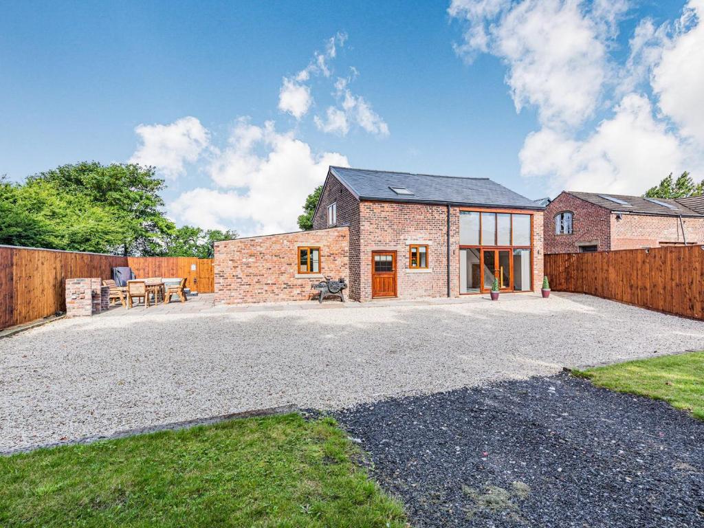 uma casa de tijolos com um pátio e uma cerca em Stuarts Farm Barn em Westhead