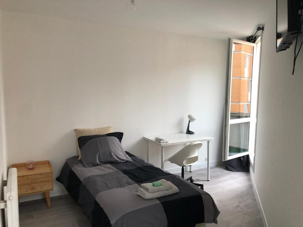 ein Schlafzimmer mit Bett, Schreibtisch und Fenster in der Unterkunft Evry Time in Courcouronnes