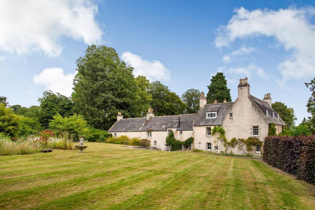 a large white house with a large grassy yard at The Garden Flat Ardullie in Ardullie