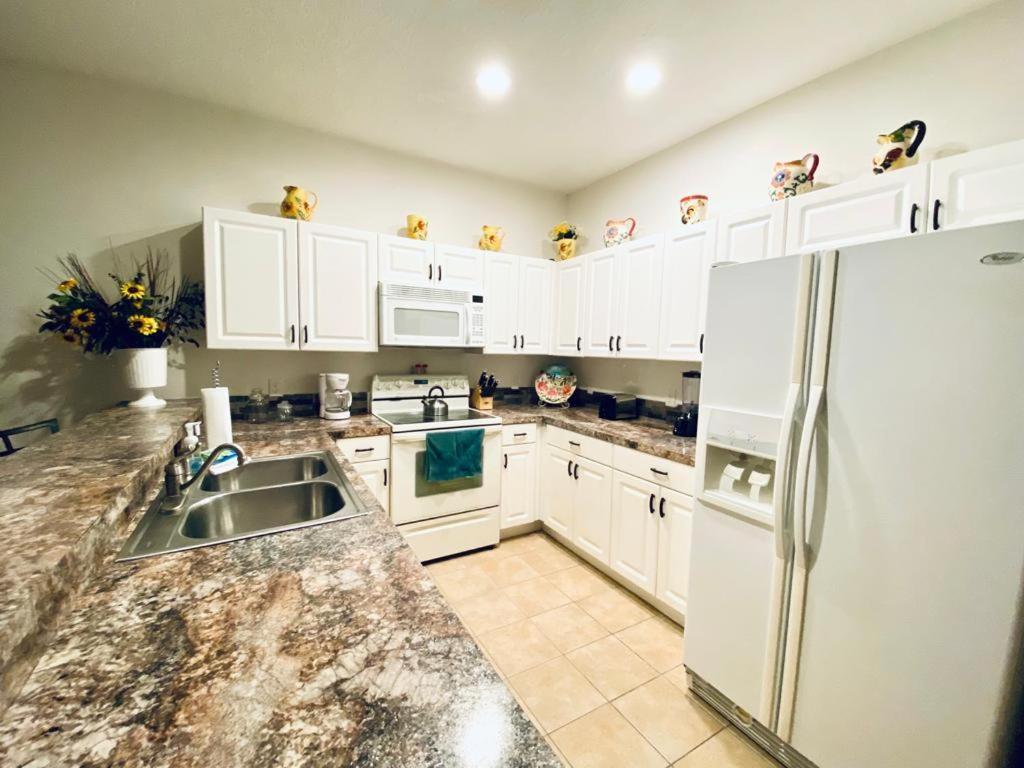 a kitchen with white cabinets and a white refrigerator at Huge Screened Patio That Overlooks Lake Buck, Near Famous Attractions!! in Orlando