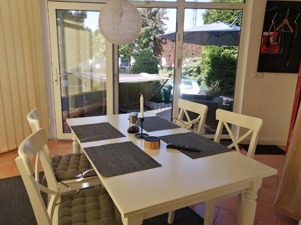 een witte eettafel met stoelen en een parasol bij Schöne Wohnung mit abgeschlossenem Grundstück zentral und ruhig in Greifswald