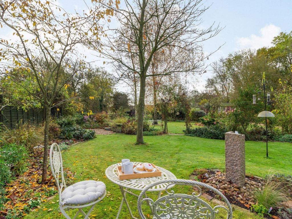 Burgh的住宿－Garden Cottage，树木繁茂的花园中的桌椅